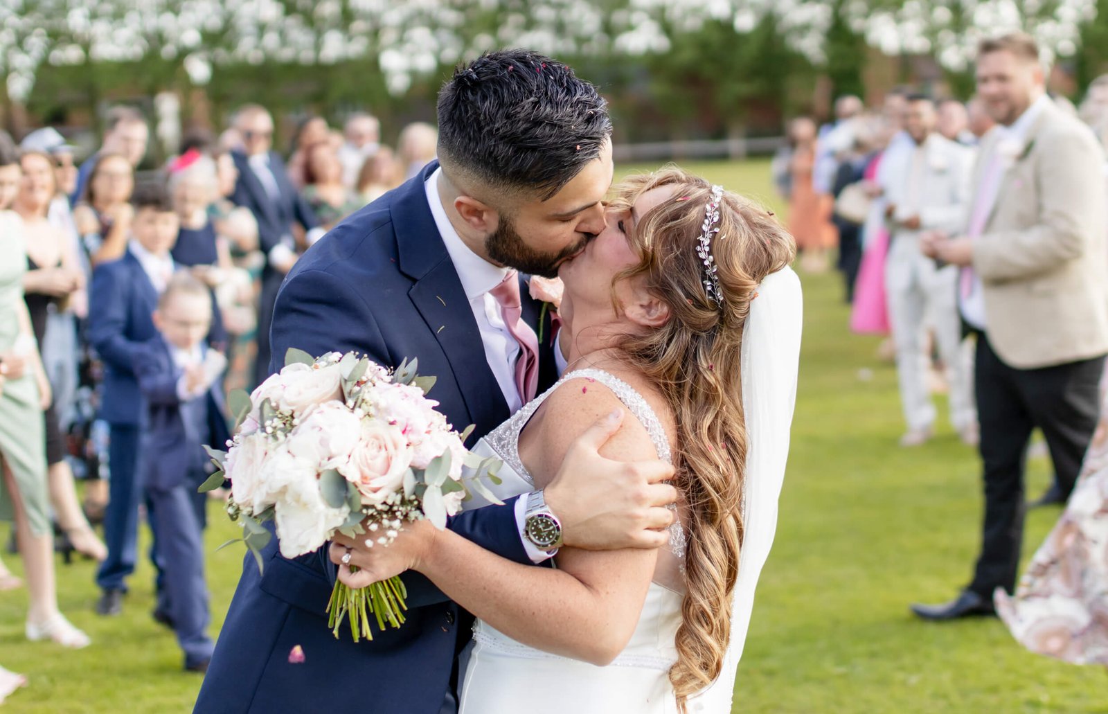 Newlyweds kissing during an outdoor wedding celebration